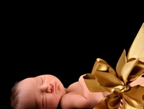 A baby is wrapped in gold ribbon and sleeping.